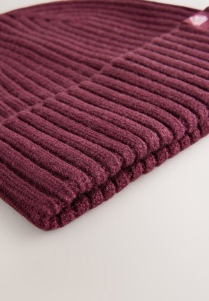 Berretto a coste color bordeaux realizzato in morbido materiale lavorato a maglia, con evidenti strisce verticali e risvolto piegato. Dettagli di texture sottili visibili.