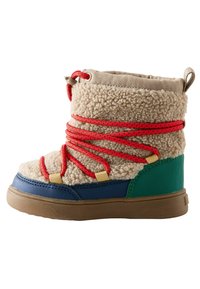 Tan gefütterter Stiefel mit roten Schnürsenkeln, grünen und blauen Akzenten sowie einer Gummisohle. Verfügt über ein plüschiges Obermaterial und kontrastierende Materialien.