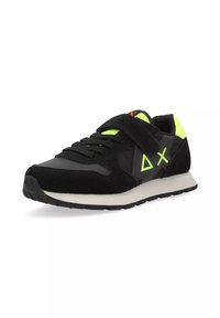 Sneaker nera con materiali in suede e mesh, dettagli verde lime e una fascia in Velcro. Presenta una suola intermedia bianca e una suola esterna in gomma.