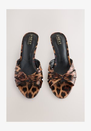 Klapki z otwartymi palcami w panterkę z wiązaniem z przodu. Wykonane z błyszczącego materiału, z gładką czarną wkładką i obcasem.