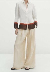 White linen shirt with a brown and orange gradient hem, paired with beige wide-leg trousers. Both garments have a textured finish.