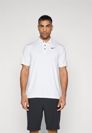 Vit Nike pikétröja med klassisk krage, tre svarta knappar och en liten svart logotyp. Kombinerad med mörkgrå shorts.