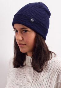 Navy ribbed knit beanie with a folded brim and a small branded patch. Material appears soft with a textured finish.