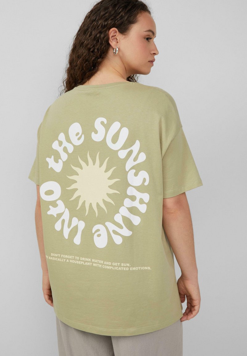 Olivegrünes Baumwoll-T-Shirt mit einem großen weißen Sonnenmotiv und Text auf der Rückseite. Kurze Ärmel, lässige Passform, glatte Textur und runder Halsausschnitt.