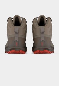 Ζευγάρι από καφέ και γκρι ορειβατικά παπούτσια με κόκκινες σόλες, ορατά από την πίσω πλευρά, με θηλιές έλξης και τη σήμανση "GTR" στη φτέρνα.