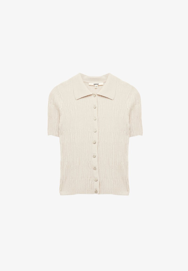 Korte mouwen, lichtbeige gebreide cardigan met een geribbelde textuur, een kraag en knoopsluitingen aan de voorkant. Zachte stof met subtiele details.