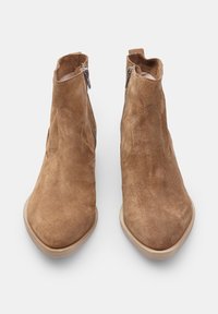 Botine din nubuc maro, cu vârful ascuțit, închidere cu fermoar pe lateral și talpă netedă de culoare bej. Finisaj texturat și caracteristici de design minim.