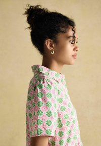 Lühikeste varrukatega särk, millel on roosa ja rohelise lilleline muster, krae ja mugav lõige. Valmistatud kergest kangast, millel on sile tekstuur.