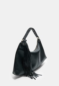 Borsa in pelle nera con tracolla intrecciata e lunghi tasselli in pelle, vista angolata che mostra il lato e il dettaglio della cerniera su sfondo semplice.