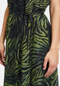 Grün und schwarz gestreftes Kleid aus leichtem Stoff, mit einem gebundenen Gürtel und lässiger Passform. Der Stoff hat eine glatte Textur.