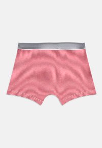 Pantaloni corti a righe rosse e bianche con un elastico a righe blu e bianche, stesi su uno sfondo bianco.