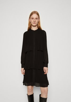 Black pleated dress with a layered design, long sleeves, high collar, and button closure, featuring sheer texture at the skirt hem.