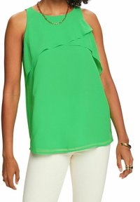 Top verde senza maniche con design a strati di volant, realizzato in tessuto leggero. Presenta un colletto rotondo e cade morbido sul corpo.