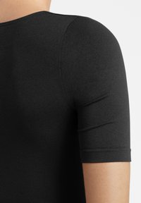 Top nero a maniche corte con scollatura rotonda, realizzato in un tessuto elastico e liscio con una leggera lucentezza, che mette in risalto un design aderente.