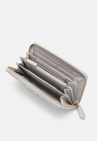 Light gray wallet with a zip closure, multiple card slots, two compartments, and a textured surface. Features gold-toned hardware accents.
