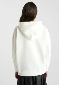 Witte hoodie met een zachte textuur, met een ontspannen pasvorm en geribbelde manchetten. De achterkant toont een minimalistisch ontwerp zonder graphics.