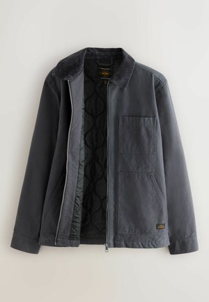 Dunkelgraue Jacke mit Kordkragen, Frontreißverschluss und einer Brusttasche. Das Innenfutter ist mit Steppmaterial versehen. Robustes Gewebe mit matter Oberfläche.