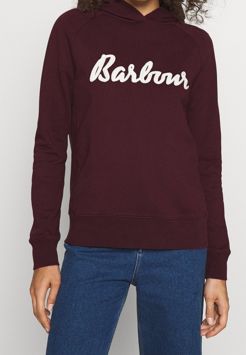 Bordový mikina s bíle vyšitým logem "Barbour". Obsahuje klokankovou kapsu, žebrované manžety a volný střih. Materiál se zdá být měkký.