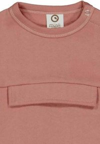 Camicia a maniche lunghe in cotone rosa con scollatura rotonda, caratterizzata da una piccola tasca e chiusura a scatto sulla spalla. Texture morbida.