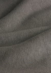 Tekstils audums tumši pelēkā krāsā, smalki austs ar gludu tekstūru, ar niansētu spīdumu un maigi plūstošām īpašībām.