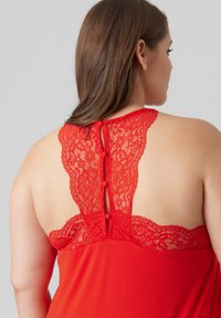 Red garment with a lace back featuring floral patterns, button detail, and a soft texture. The design showcases a semi-open back style.