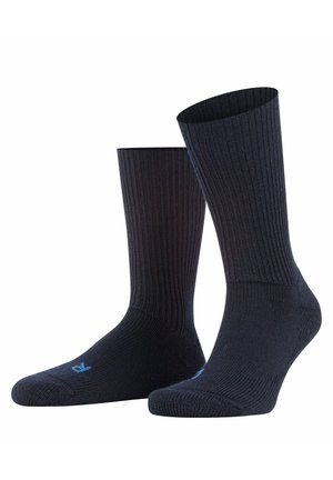 Schwarze gerippte Socken mit weicher Textur, ausgestattet mit verstärktem Zehen- und Fersenbereich. Inklusive kleinem blauen Logo nahe der Zehe.