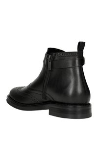 Černá kožená kotníková bota s detaily ve stylu wingtip, bočním zipem, poutkem na patě a plochou gumovou podrážkou. Hladký povrch a elegantní design.