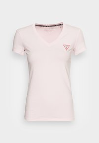 Lyserød kvindelig V-hals T-shirt med korte ærmer og lille rød og hvid Guess-logo på venstre bryst.