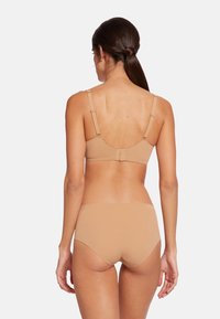 Beige bh- och tros-set visat från baksidan, med justerbara band, slät tyg och sömlösa kanter för en strömlinjeformad look.