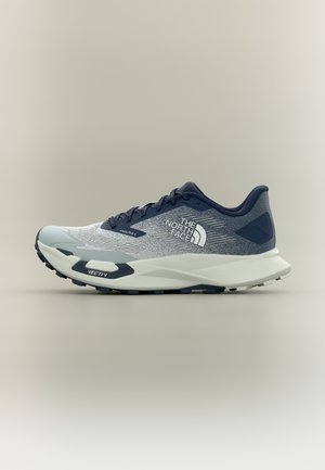 Hellgrauer und marineblauer Laufschuh mit weißer Sohle, "The North Face"-Logo an der Seite und robustem Profil, das für Trailrunning entwickelt wurde.