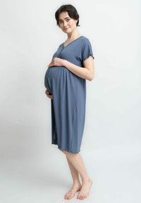 Schwangerschaftskleid aus weichem, leichtem Stoff mit V-Ausschnitt, kurzen Ärmeln und einer fließenden Form, die einen wachsenden Bauch umschließt.