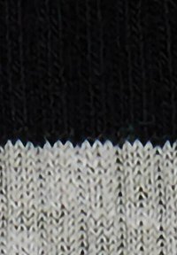 Tessuto lavorato a maglia con strisce orizzontali bianche e nere, con una finitura testurizzata, che presenta un bordo ondulato distintivo nella transizione dei colori.