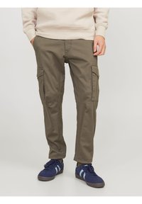 Pantalones cargo verde oliva con múltiples bolsillos laterales, un corte ajustado y detalles de costura. Combinados con zapatillas azules.