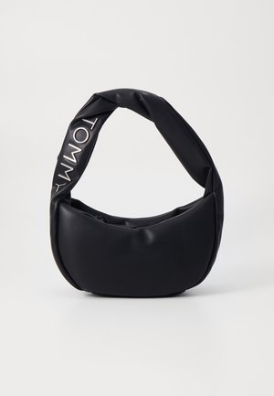 Bolso suave negro con asa acolchada y torsionada que lleva la palabra Tommy en letras blancas en la correa.