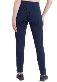 Marineblauwe sportbroeken van rekbaar materiaal, met een elastische tailleband en ritsen bij de enkels. Gladde textuur en aansluitend ontwerp.