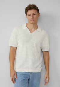 Polo shirt blanc texturé à manches courtes et design en V, avec des rayures horizontales et un ourlet côtelé.