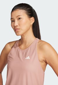 Roze sporttop met een gestructureerde stof, voorzien van een wit logo. Het ontwerp heeft een ronde halslijn en brede schouderbanden.