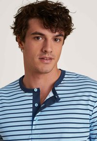 Striped short-sleeve shirt in light blue and navy, featuring a buttoned Henley neckline and smooth cotton texture.