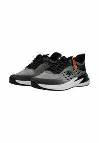 Paire de baskets athlétiques gris et noir avec semelles blanches, lacets noirs et une étiquette orange sur le côté de la chaussure droite.