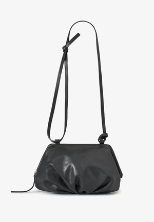Sac bandoulière en cuir noir avec un design froncé et plissé, doté d'une sangle fine ajustable, sur fond blanc.