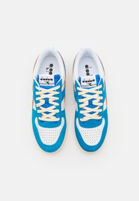 Kék és fehér sneaker, nubuk és hálós anyagból, perforált orral, krém színű fűzőkkel és színes akcentusokkal. Diadora logó a nyelvén.