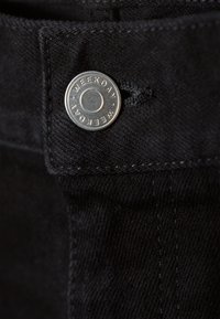 Black denim fabric with a smooth texture, featuring a silver metal button with "WEEKDAY" engraved, positioned at the top.