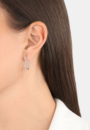 Silberne Creole mit einem schlanken, elongated Design, das klare Edelsteine entlang einer Kante aufweist und an einer einfachen Steckfassung hängt.