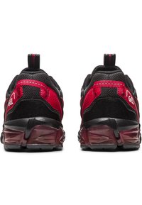 Scarpe da corsa nere e rosse con una parte superiore in mesh testurizzato, intersuola ammortizzata e dettagli riflettenti sul tallone con un lembo per il sollevamento.