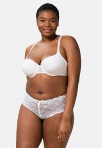 Soutien-gorge wireless bianco con coppe lisce e dettagli in pizzo al centro; abbinato a un perizoma di pizzo bianco con bordi ondulati e motivi floreali.