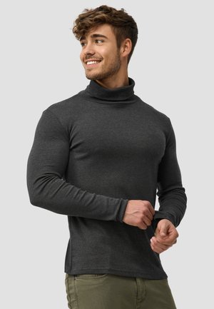 Suéter de cuello alto en gris oscuro con mangas largas, diseño ajustado y textura suave, combinado con pantalones verdes claros.