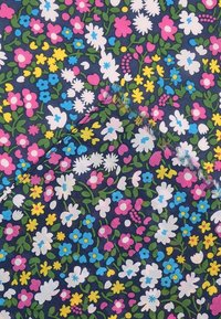 Tissu bleu marine avec un petit motif floral en blanc, rose, jaune et bleu, accompagné de feuilles vertes, présentant un coin plié montrant des bords effilochés.