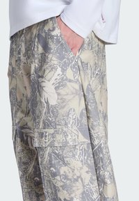 Lette bukser med et afdæmpet beige og gråt botanisk print, med sidelommer og en afslappet pasform. Struktureret bomuldsmateriale.