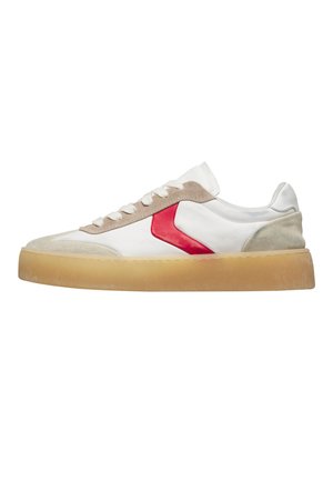 Scarpa da ginnastica bianca con dettagli in camoscio beige, particolare laterale rosso, lacci bianchi e suola spessa traslucida color sabbia su sfondo bianco.