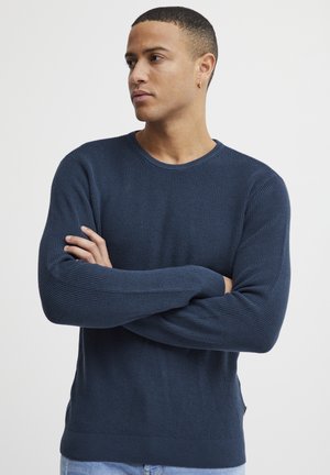 Maglione a maglia blu navy, collo a giro, texture a costine, maniche lunghe, dettaglio con spacco laterale, aderente in vita.